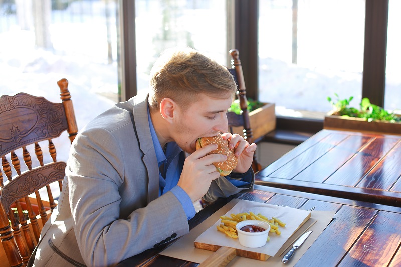 ハンバーガーにかじりつく男性