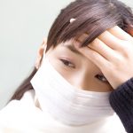 手で熱をはかる女性