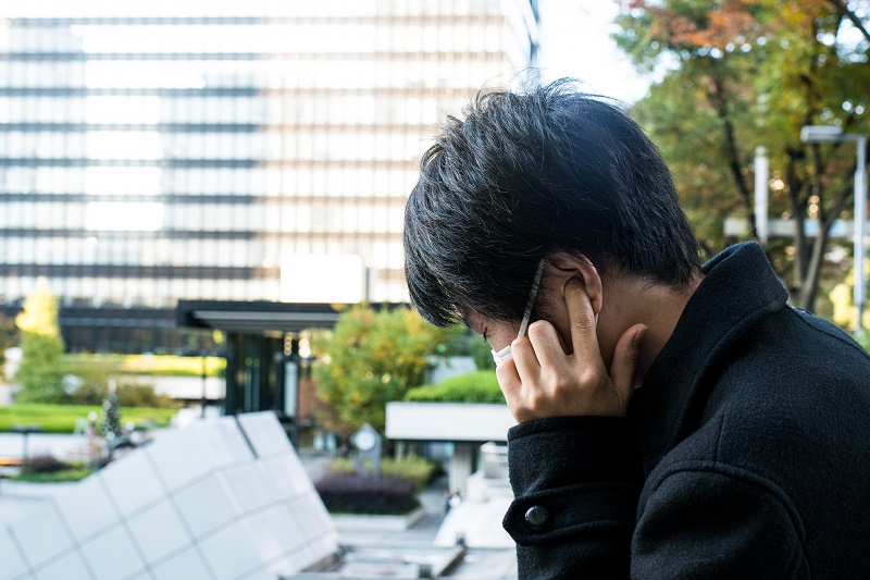 耳の穴を押さえる男性