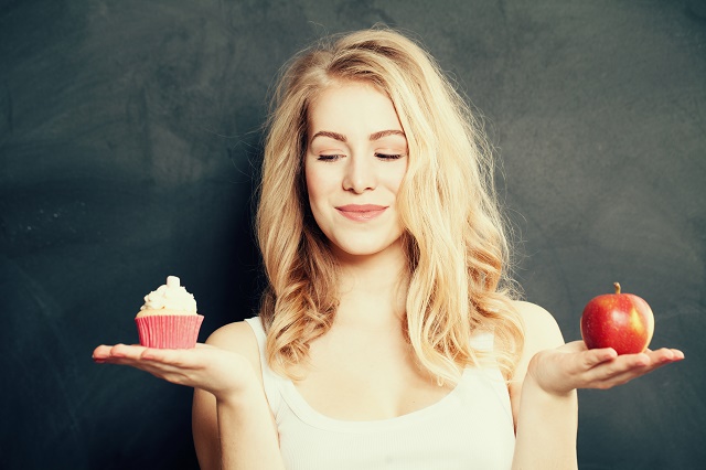 ケーキとリンゴを両手に持つ女性