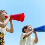 土手でメガホンで叫ぶ2人の子供