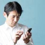 スマホの見え方が良くないので顔をしかめる男性