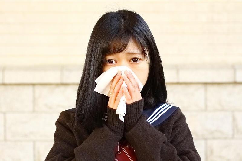 花粉症で鼻をかむ女子生徒